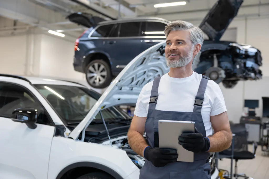 Retired auto technician using hand tools on a car in a collision repair shop.